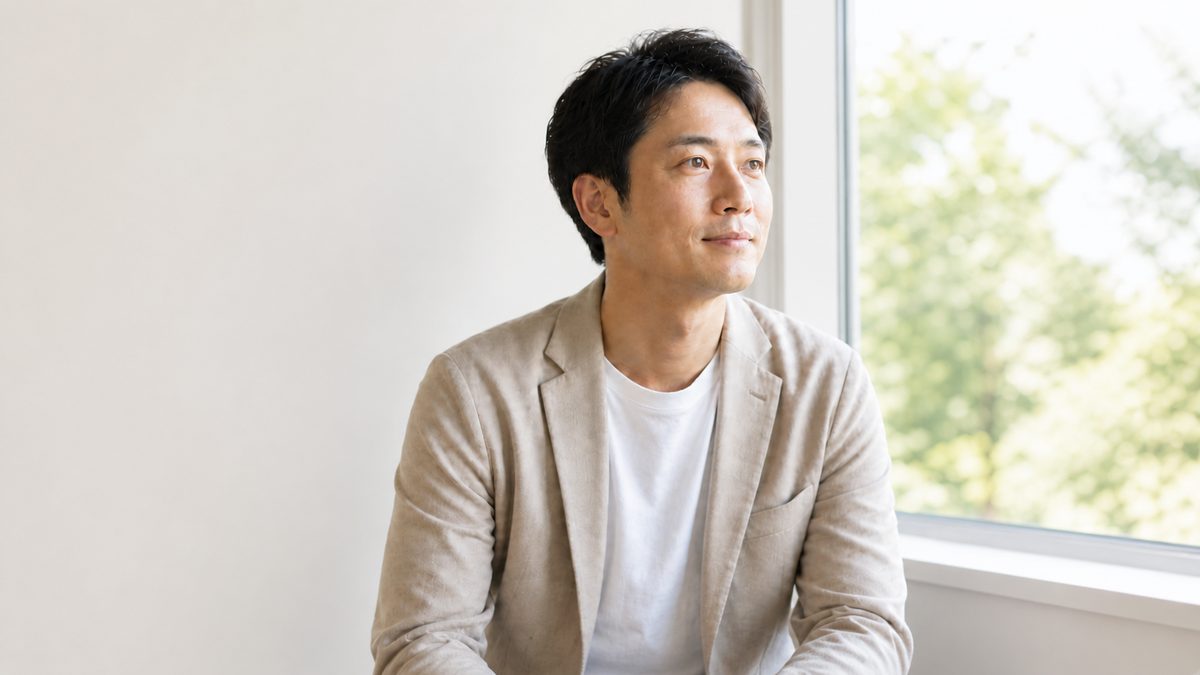 明るい窓辺に座る男性