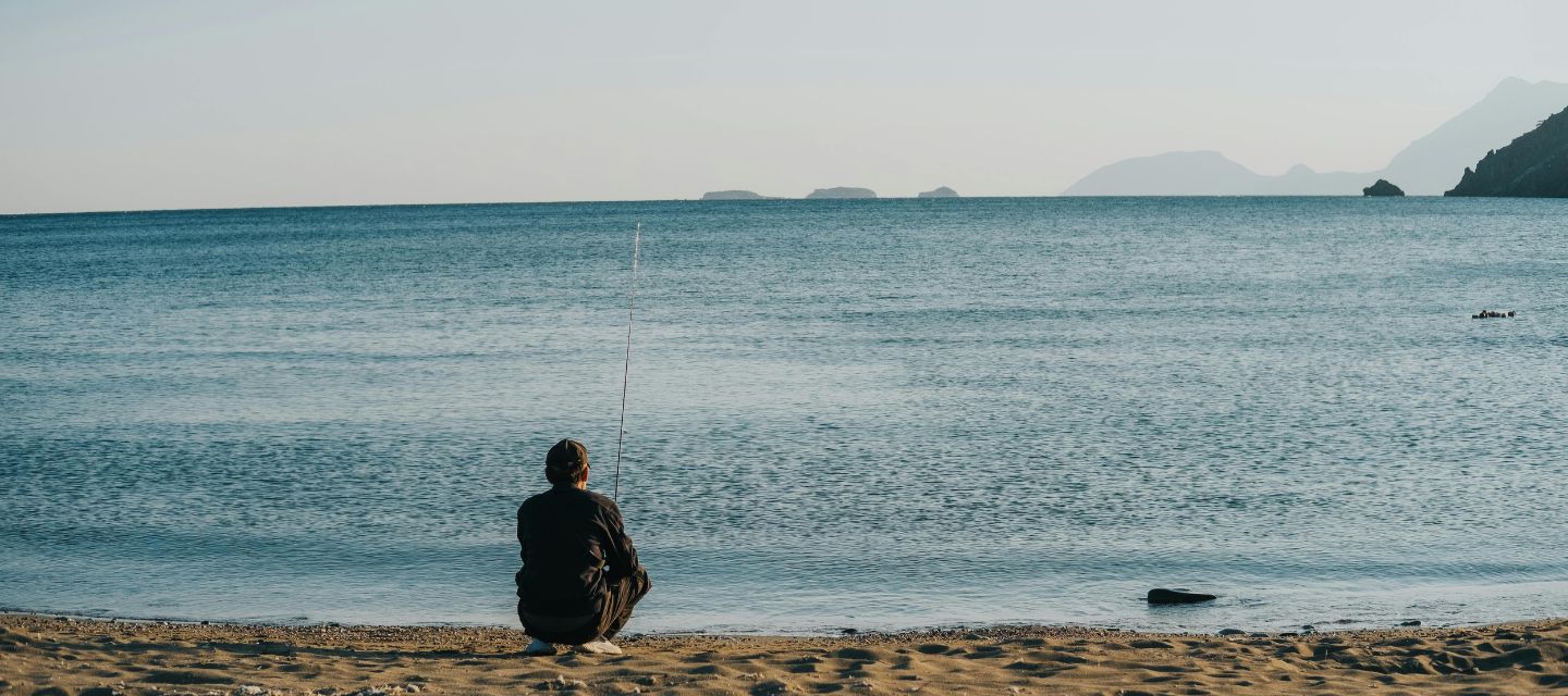 海辺で一人座る人物の後ろ姿